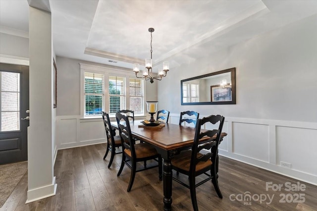 dining room featuring dark hardwood / wood-style floors, a tray ceiling, and a chandelier