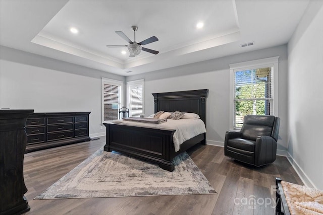 bedroom featuring ceiling fan, a tray ceiling, and dark hardwood / wood-style flooring