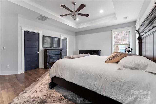 bedroom featuring ceiling fan, a tray ceiling, and dark hardwood / wood-style floors