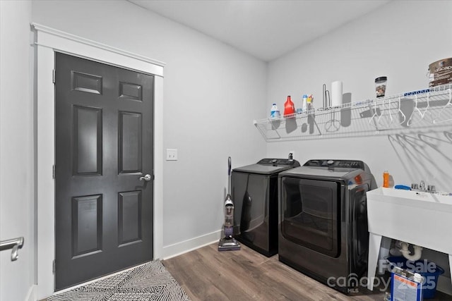 clothes washing area featuring sink, dark wood-type flooring, and washer and dryer