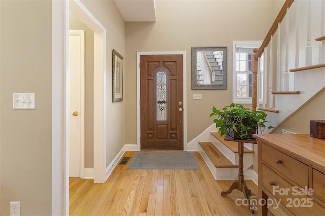 foyer entrance featuring baseboards, visible vents, light wood finished floors, and stairs