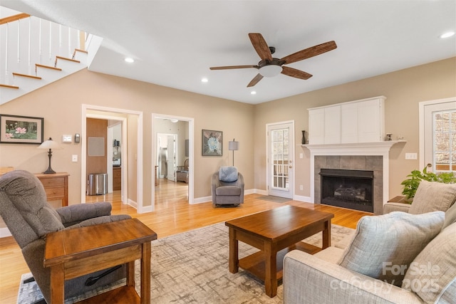 living area with recessed lighting, light wood-style flooring, and a tiled fireplace