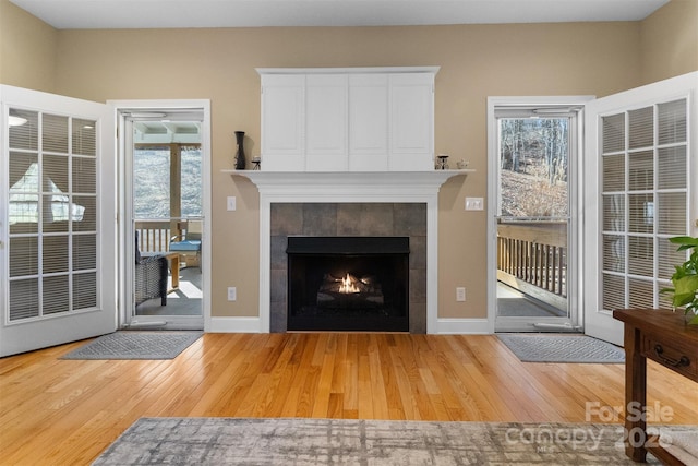 unfurnished living room with hardwood / wood-style flooring, baseboards, and a tile fireplace