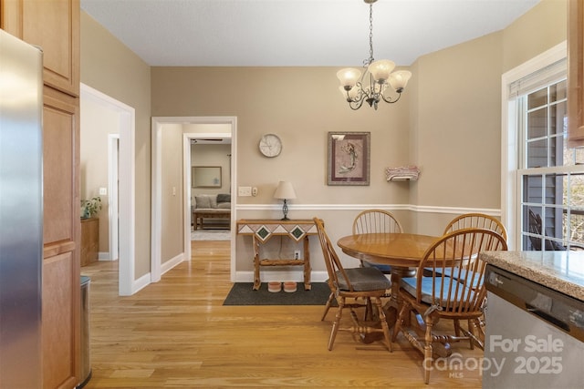 dining space featuring light wood-type flooring, baseboards, and a chandelier