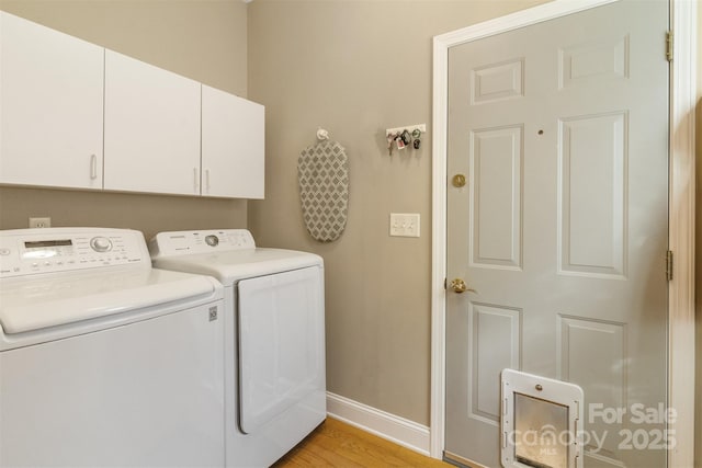 laundry area with cabinet space, washing machine and dryer, baseboards, and light wood-style flooring