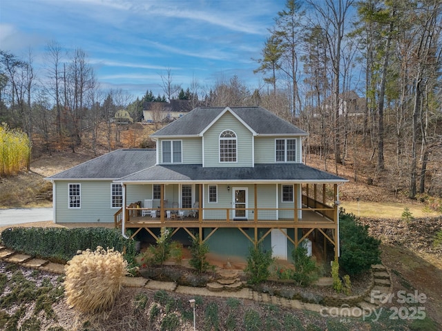 view of front facade with roof with shingles and a deck