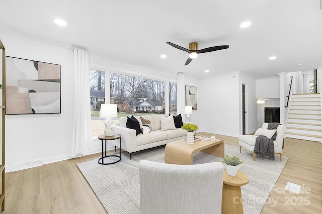 living room featuring ornamental molding, ceiling fan, and light wood-type flooring