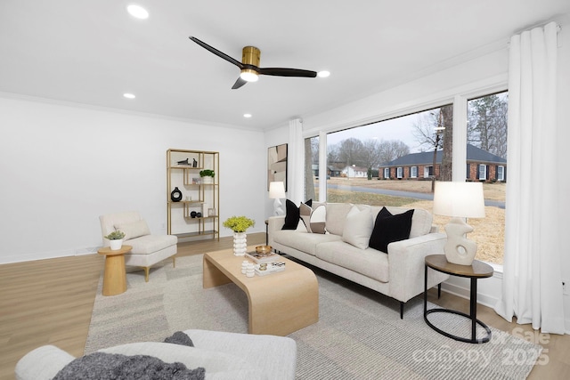 living room featuring light hardwood / wood-style flooring, ornamental molding, and ceiling fan