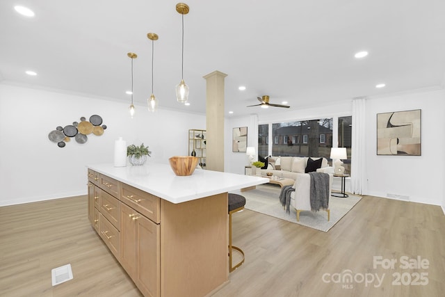 kitchen with crown molding, a center island, hanging light fixtures, a kitchen breakfast bar, and light hardwood / wood-style floors