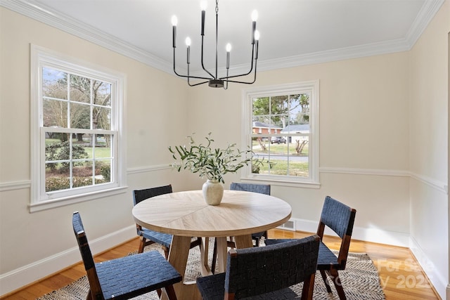 dining space featuring wood-type flooring, an inviting chandelier, and crown molding