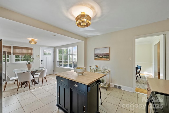 kitchen featuring light tile patterned floors, a breakfast bar, range, butcher block counters, and a center island