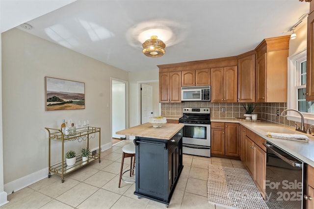 kitchen with butcher block countertops, sink, backsplash, stainless steel appliances, and a kitchen island