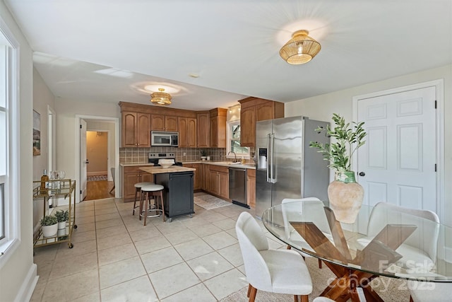 kitchen with a kitchen bar, sink, tasteful backsplash, appliances with stainless steel finishes, and a kitchen island