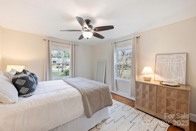 bedroom with multiple windows, ceiling fan, and light hardwood / wood-style floors