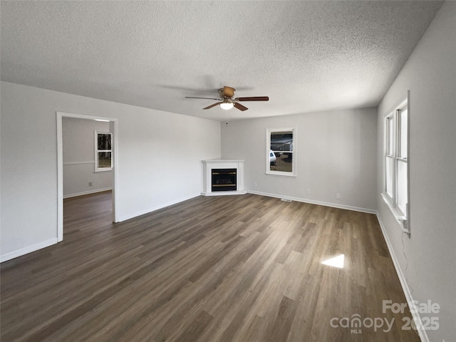 unfurnished living room with ceiling fan, dark hardwood / wood-style floors, and a textured ceiling