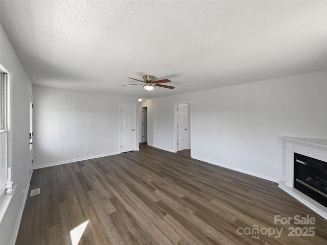 unfurnished living room with ceiling fan, dark hardwood / wood-style floors, and a textured ceiling