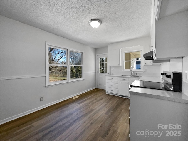 kitchen featuring dark wood-type flooring, sink, white cabinetry, range, and a textured ceiling