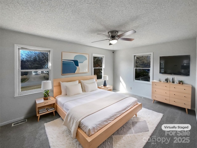 carpeted bedroom featuring ceiling fan and a textured ceiling