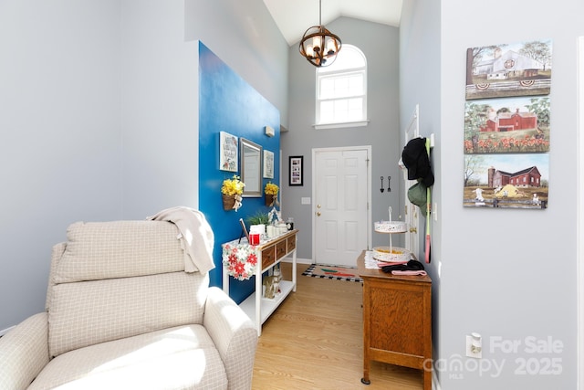 entryway with high vaulted ceiling, an inviting chandelier, and light hardwood / wood-style floors