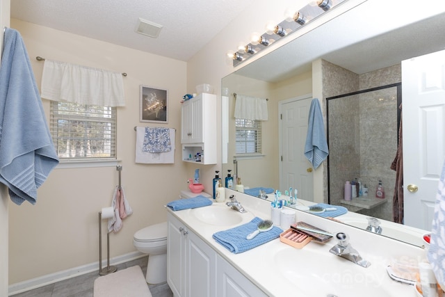 bathroom featuring walk in shower, vanity, toilet, and a textured ceiling