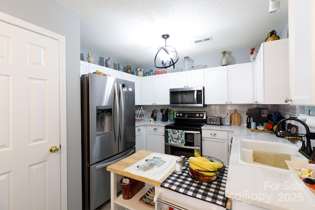 kitchen featuring hanging light fixtures, white cabinetry, appliances with stainless steel finishes, and sink