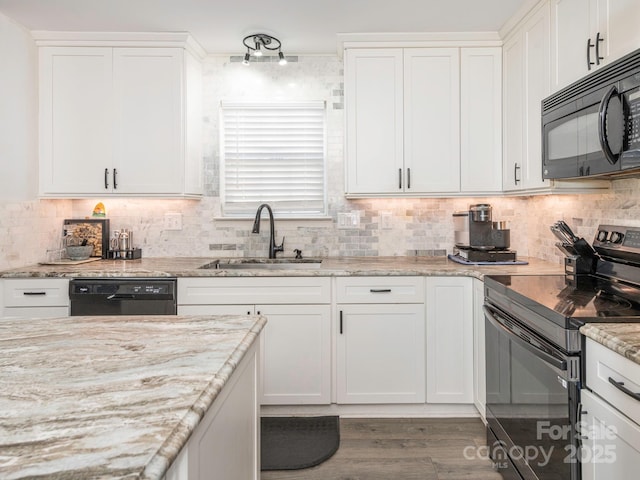 kitchen featuring sink, white cabinetry, light wood-type flooring, light stone countertops, and black appliances