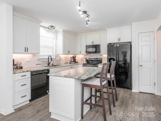 kitchen with white cabinetry, a kitchen island, sink, and black appliances