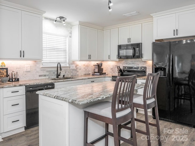 kitchen featuring white cabinetry, sink, black appliances, and a kitchen island