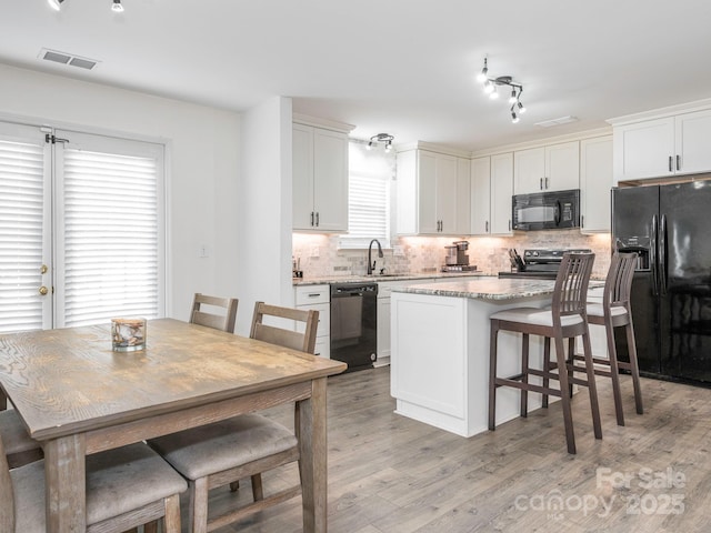 kitchen featuring sink, black appliances, white cabinets, and a kitchen island