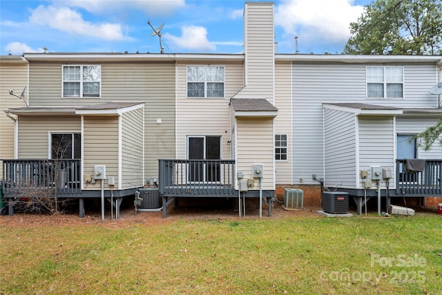 back of property with cooling unit, a wooden deck, and a lawn