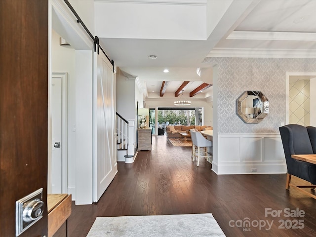 hallway with dark hardwood / wood-style floors, a chandelier, crown molding, a barn door, and beam ceiling