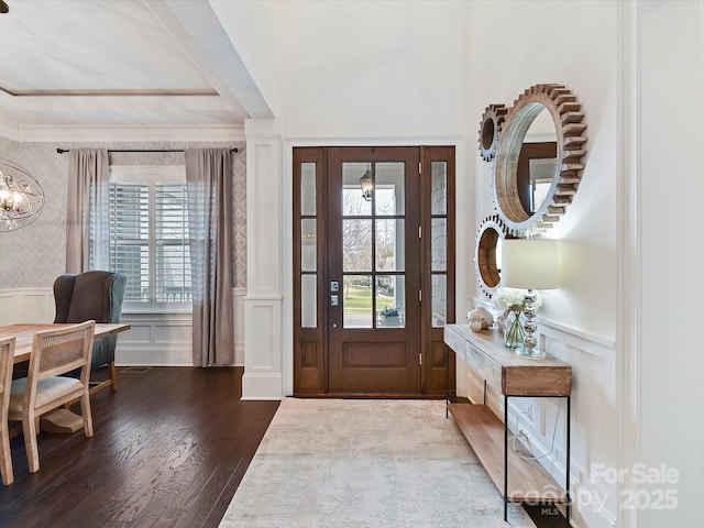 entryway with dark hardwood / wood-style flooring, ornamental molding, a healthy amount of sunlight, and an inviting chandelier