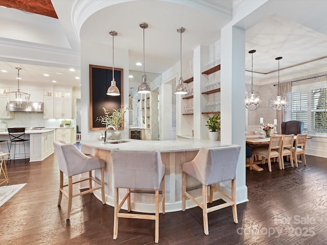 kitchen featuring crown molding, sink, kitchen peninsula, and decorative light fixtures