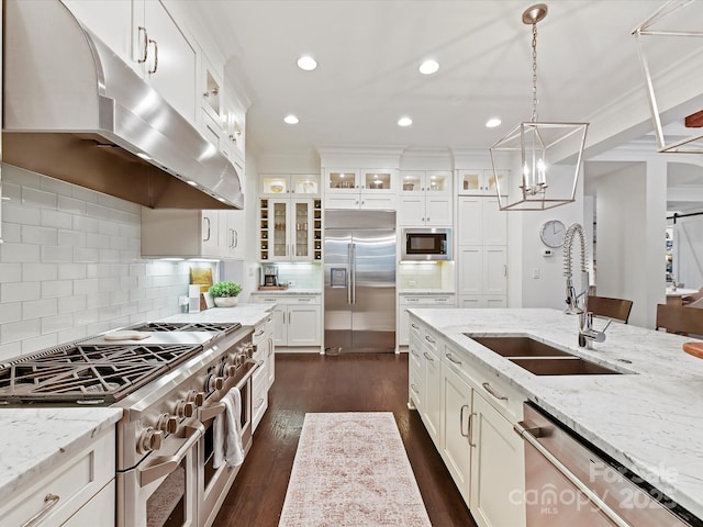 kitchen featuring built in appliances, light stone countertops, sink, and white cabinets