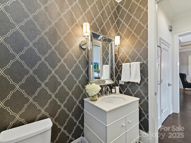 bathroom with crown molding, wood-type flooring, vanity, and toilet