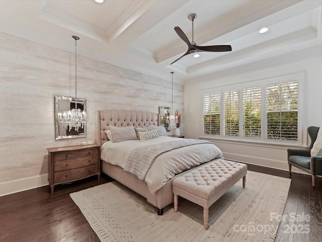 bedroom with dark hardwood / wood-style floors, ceiling fan with notable chandelier, and a tray ceiling