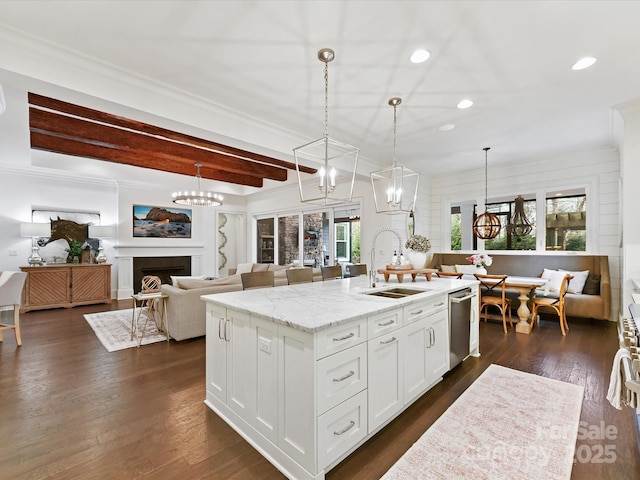 kitchen featuring sink, decorative light fixtures, white cabinets, and a center island with sink