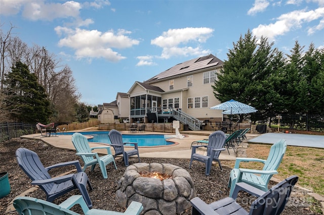 view of swimming pool featuring a sunroom, a patio, and an outdoor fire pit