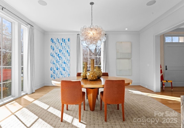 dining room with crown molding, light hardwood / wood-style flooring, and a notable chandelier