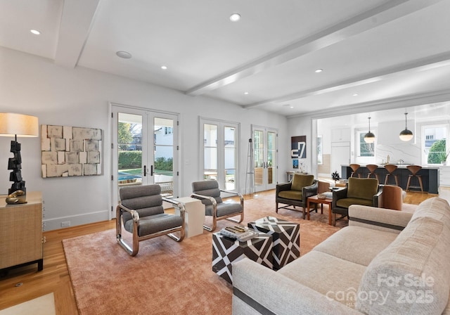 living room featuring beamed ceiling, light hardwood / wood-style flooring, and french doors