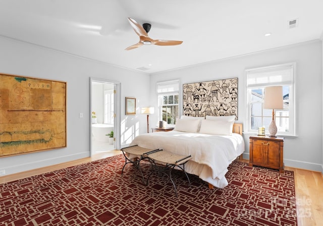 bedroom with dark hardwood / wood-style flooring, crown molding, ensuite bath, and ceiling fan