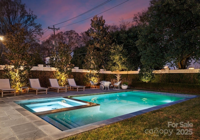 pool at dusk featuring an in ground hot tub