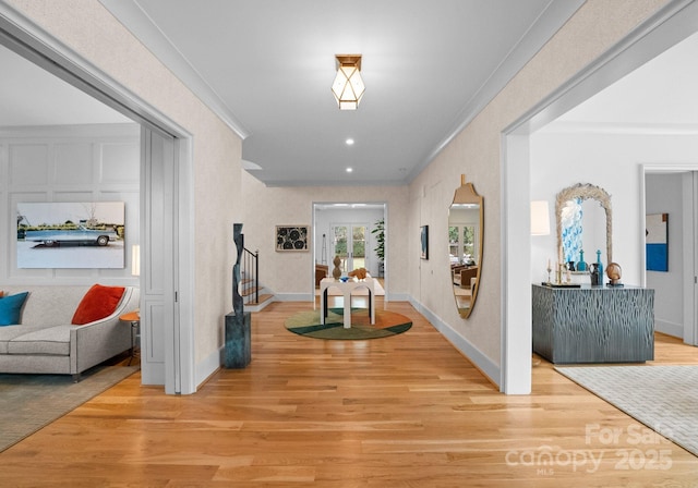 corridor with ornamental molding and light hardwood / wood-style flooring