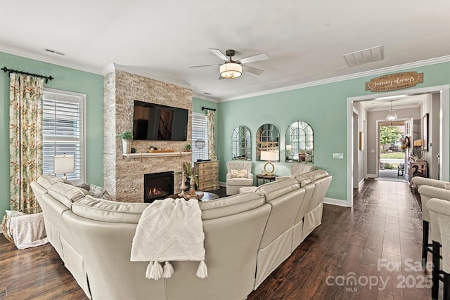 living room featuring dark hardwood / wood-style flooring, crown molding, ceiling fan, and a fireplace