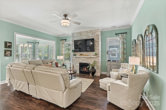 living room featuring dark wood-type flooring, a fireplace, ceiling fan with notable chandelier, and crown molding