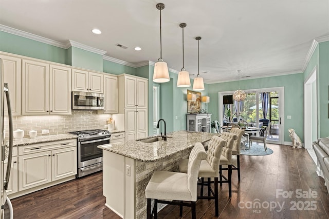 kitchen featuring sink, decorative light fixtures, a center island with sink, appliances with stainless steel finishes, and light stone countertops