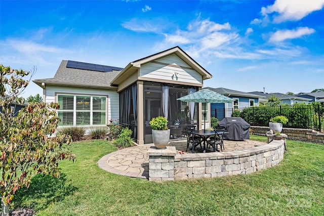 rear view of house with a lawn, a sunroom, a patio, and solar panels