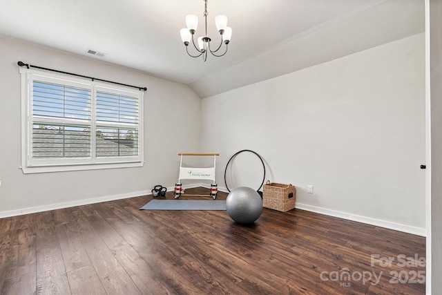 exercise room featuring lofted ceiling, dark wood-type flooring, and a notable chandelier