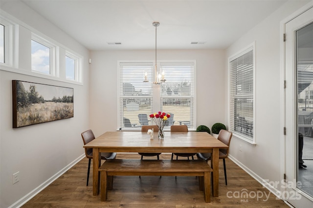 dining space with a notable chandelier, plenty of natural light, and dark hardwood / wood-style floors