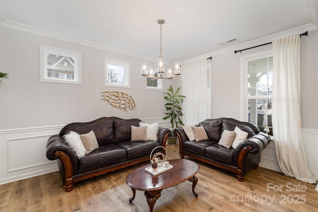 living room featuring crown molding, light hardwood / wood-style floors, and a chandelier